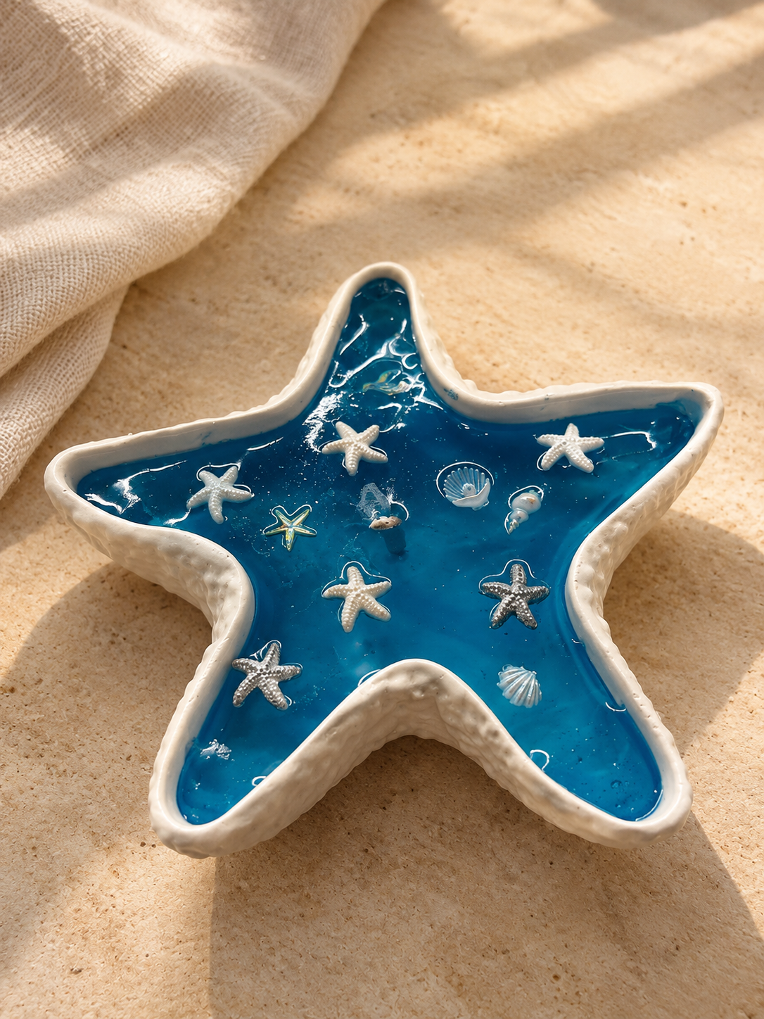 White starfish-shaped dish filled with blue wax and small sea stars and shells