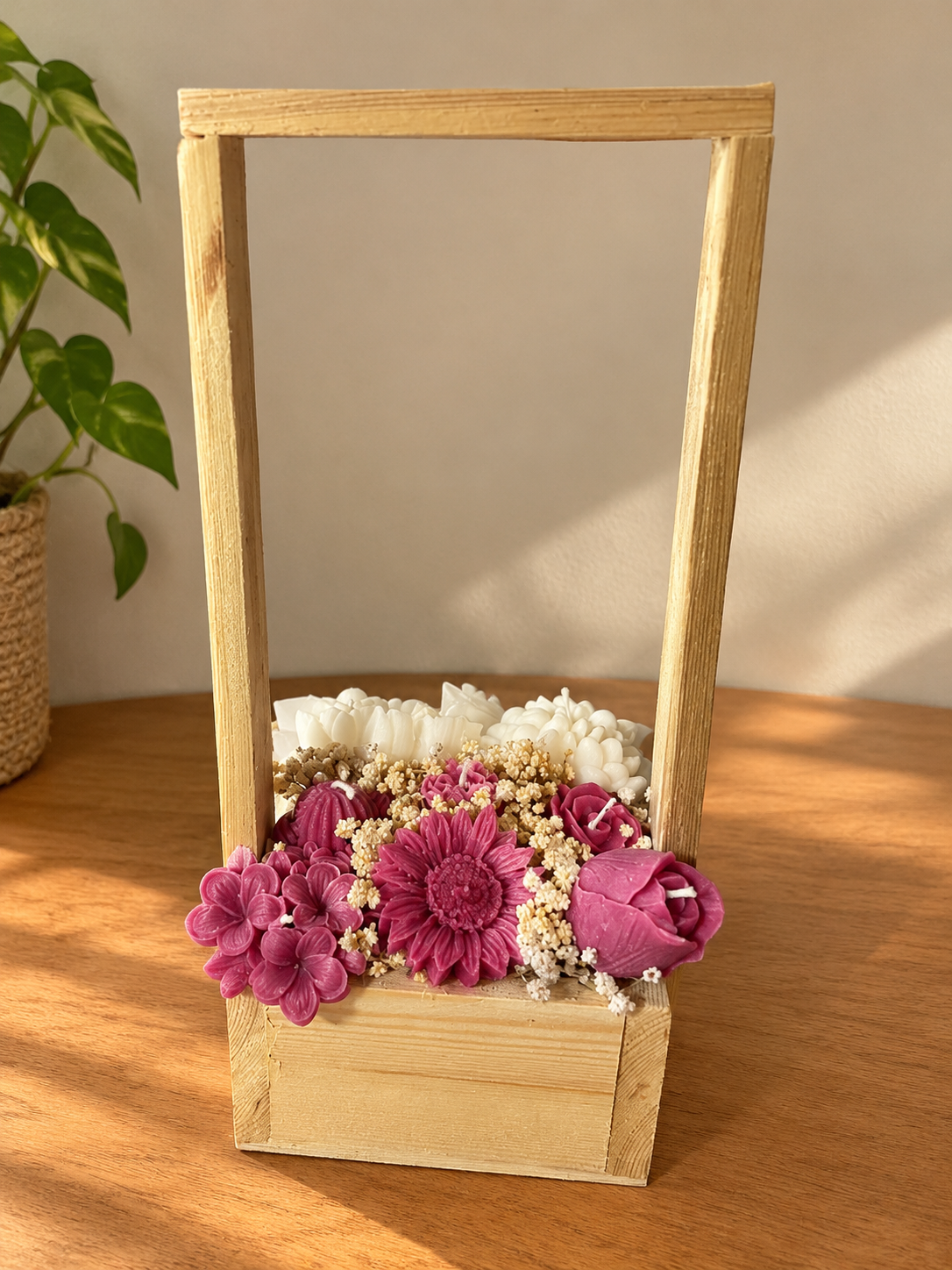 Tall wooden carrier filled with berry-pink and white wax flower candles and dried flowers