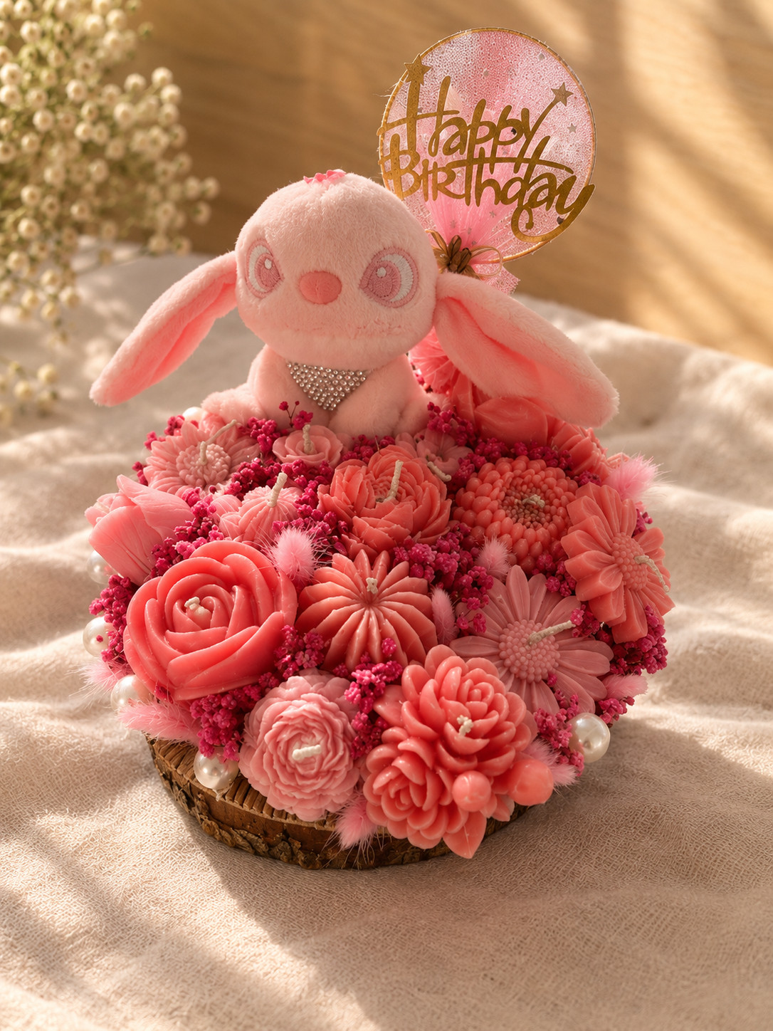 Pink plush bunny on a dome of pink wax flower candles with a Happy Birthday topper
