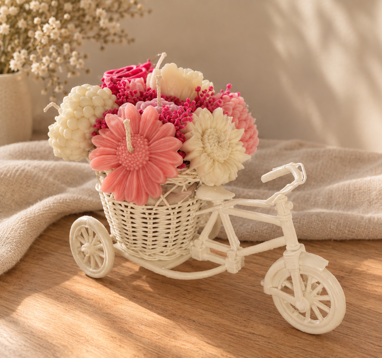 White bicycle with a basket of pink and cream wax flower candles