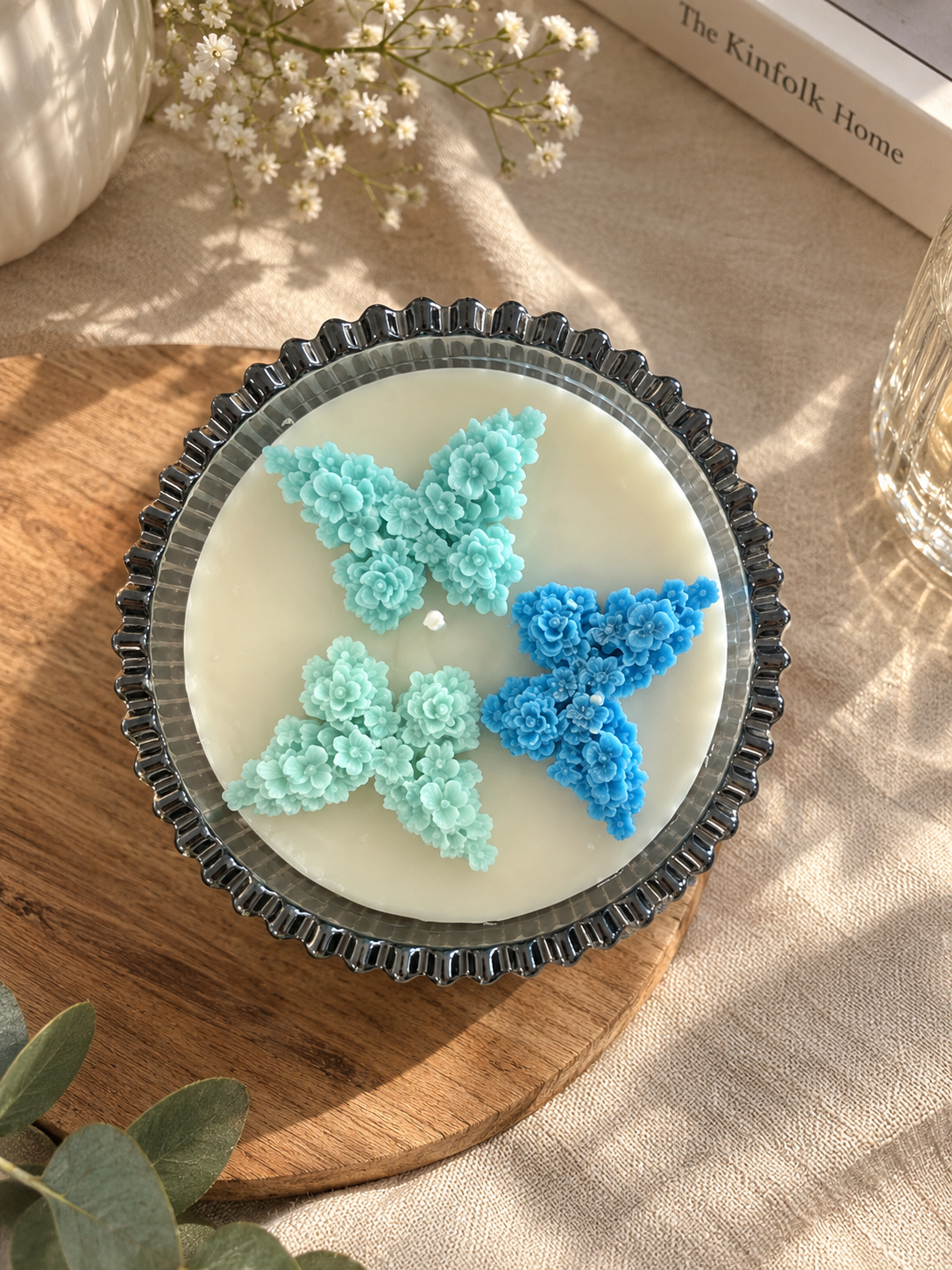 Cream candle in a fluted glass bowl topped with blue floral butterflies