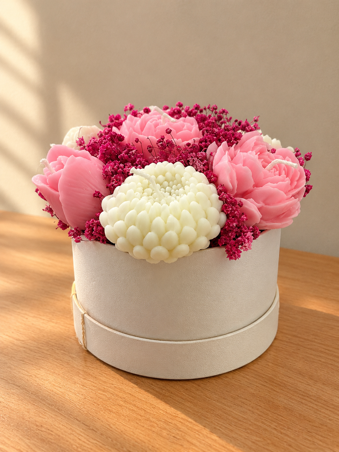 Round cream hatbox filled with pink peony and white chrysanthemum wax candles and magenta dried flowers