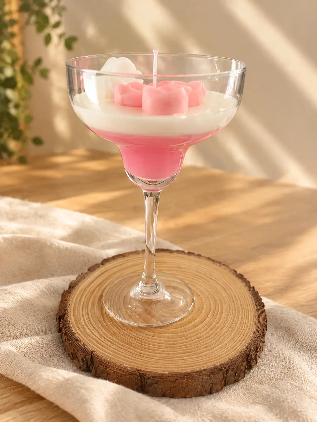 Cocktail glass candle with pink and white layers topped with pink wax flowers